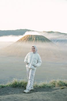 A woman in warm clothing stands before the misty Mount Bromo in Indonesia.
