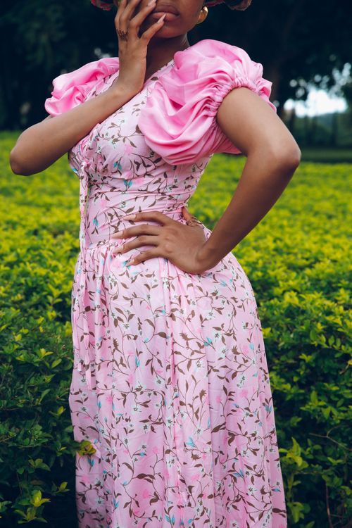 Free Close-up of a woman in a floral pink dress standing in a lush garden. Stock Photo