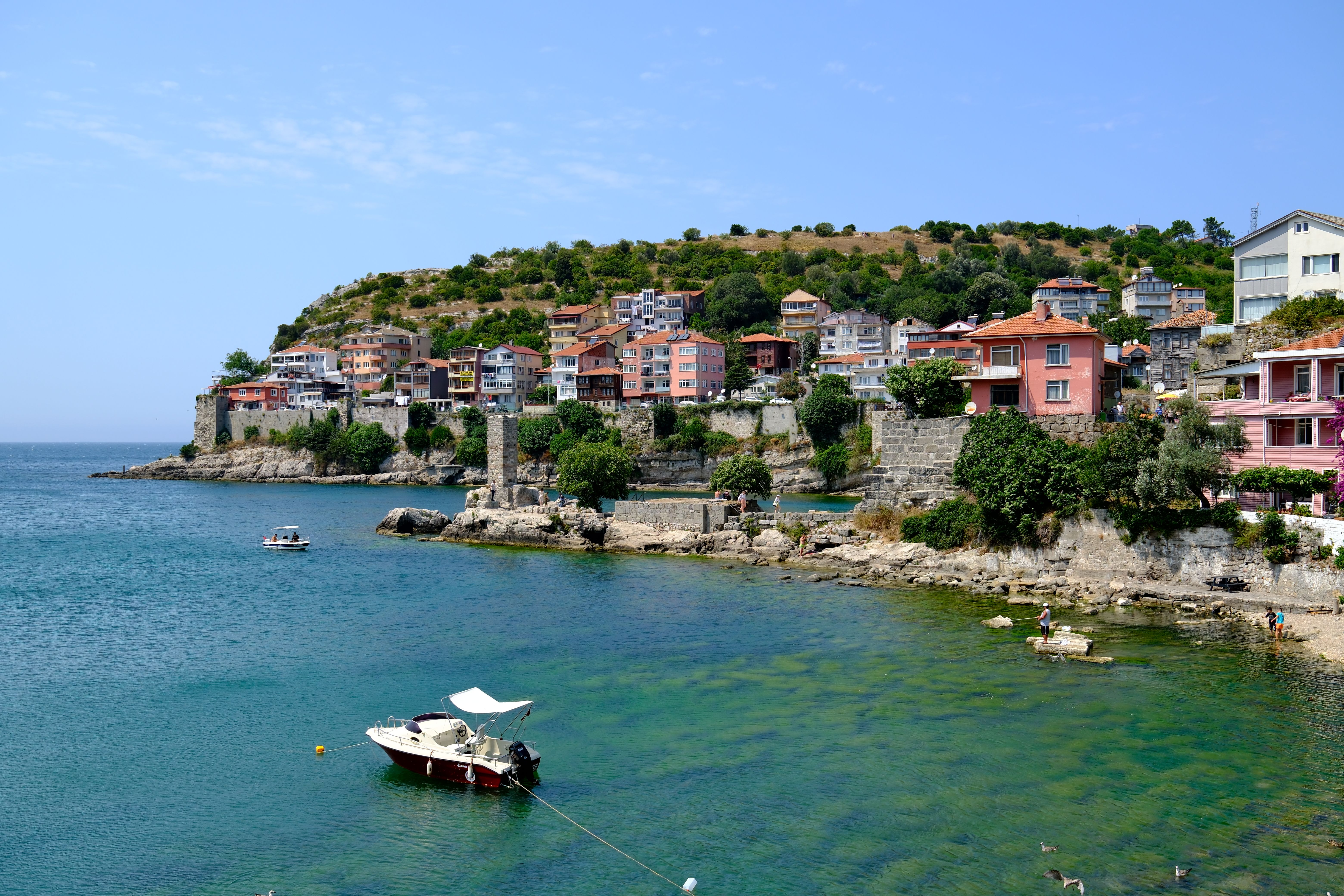Scenic view of Amasra's coastline with boats and colorful houses on a sunny day.