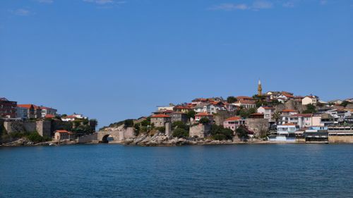 Free Charming coastal town with historic architecture overlooking a calm sea under a clear blue sky. Stock Photo