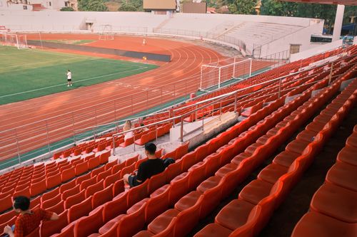 Free Quiet football stadium in Hải Phòng, Vietnam, with red seats and a lush green field. Stock Photo