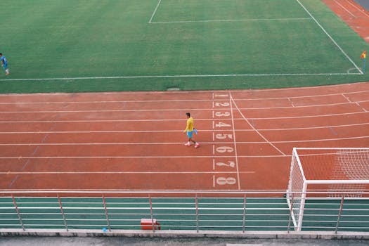 Athlete on a running track near a football field in Hải Phòng under bright daylight.