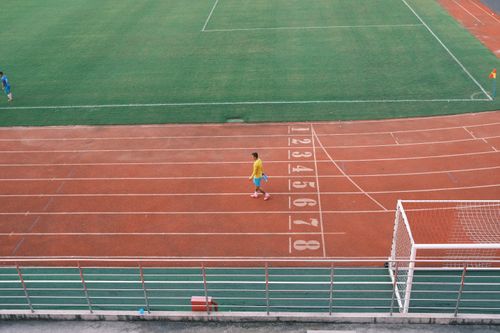 Free Athlete on a running track near a football field in Hải Phòng under bright daylight. Stock Photo