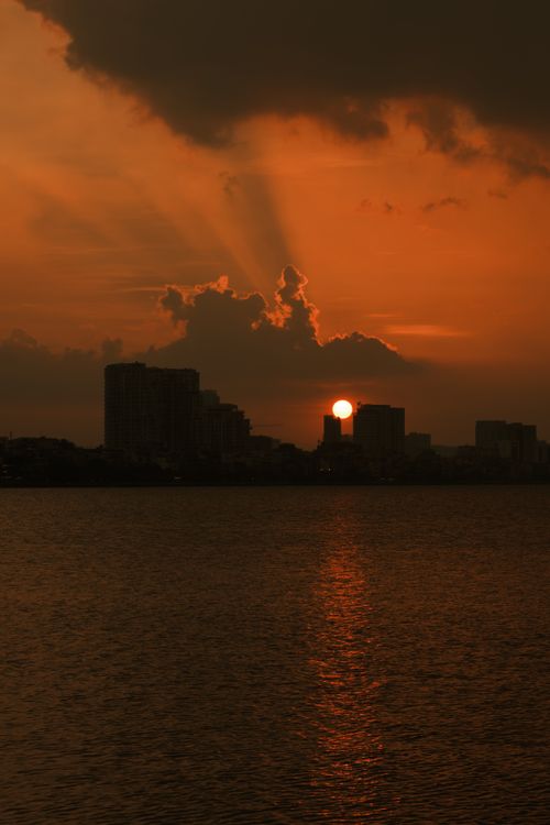 Free Stunning sunset view over Hanoi's skyline with dramatic clouds reflecting in the water. Stock Photo