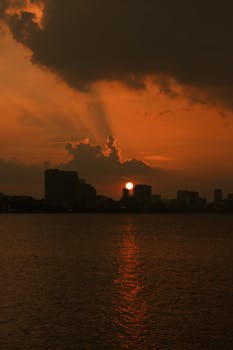 Beautiful autumn sunset over Hanoi's cityscape with vibrant sky and calm waters.