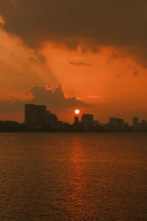 Free Breathtaking autumn sunset over the Hanoi skyline with orange skies and city silhouette. Stock Photo