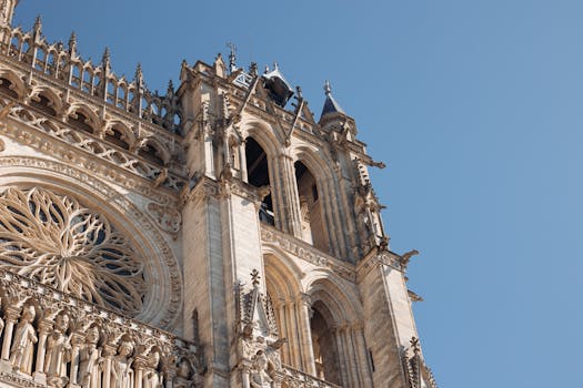 Close-up view of Amiens Cathedral's facade with intricate Gothic details under a clear blue sky.