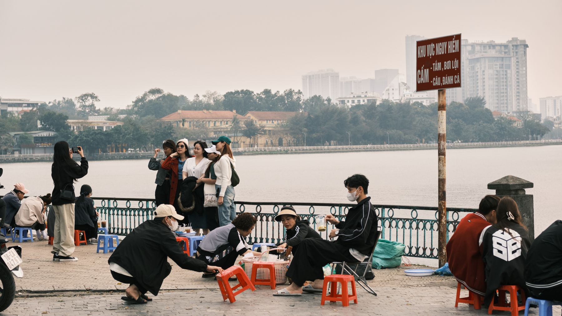 A candid scene of people enjoying street food by West Lake in Hanoi, capturing the essence of local culture.