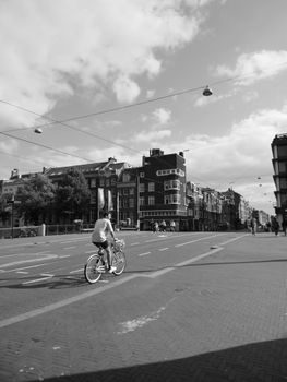 A cyclist rides through a picturesque urban street under a cloudy sky.