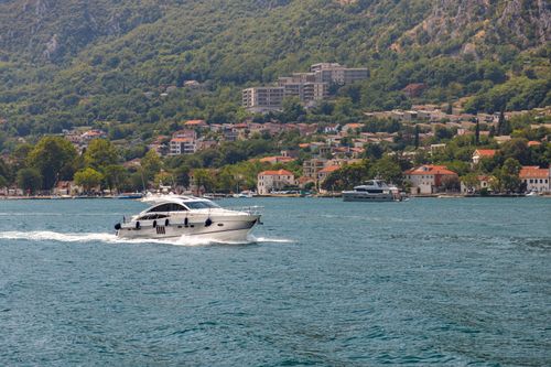 Free Scenic yacht cruising near picturesque coastal town with lush green hills and clear blue water. Stock Photo