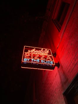 Bright red neon pizza sign glowing at night, Washington DC. Captures vibrant city nightlife.