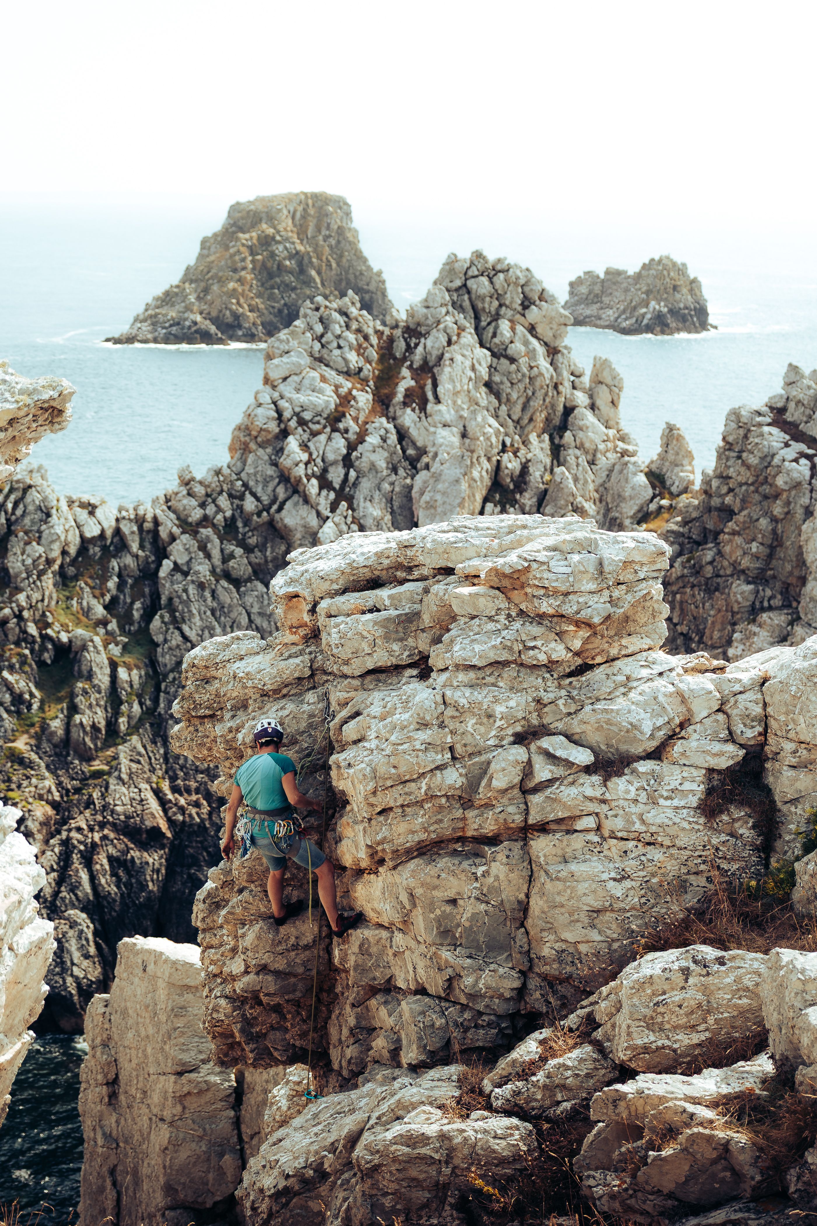 A male climber scaling rocky cliffs with the ocean in the background, showcasing adventure and nature.