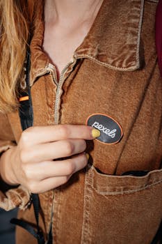 Close-up view of person holding 'pexels' patch on a brown jacket.