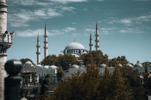 Free Stunning view of the Süleymaniye Mosque surrounded by lush trees against a blue sky in İstanbul. Stock Photo