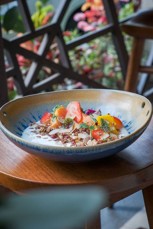 Free A colorful breakfast bowl featuring fresh fruits and granola on a wooden table in Bali. Stock Photo
