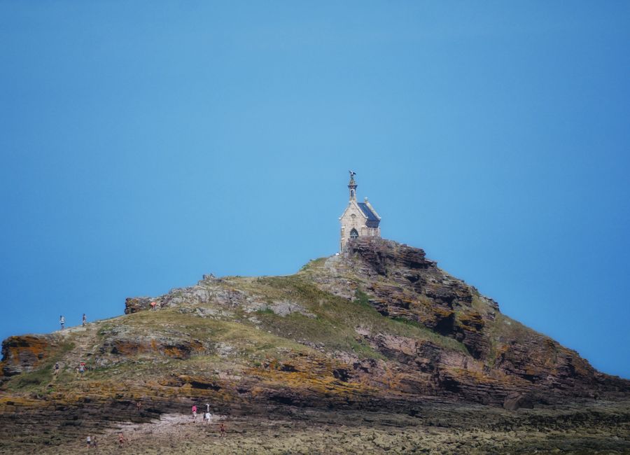 Chapel on rocky hill under blue sky in Erquy, Bretagne, France.