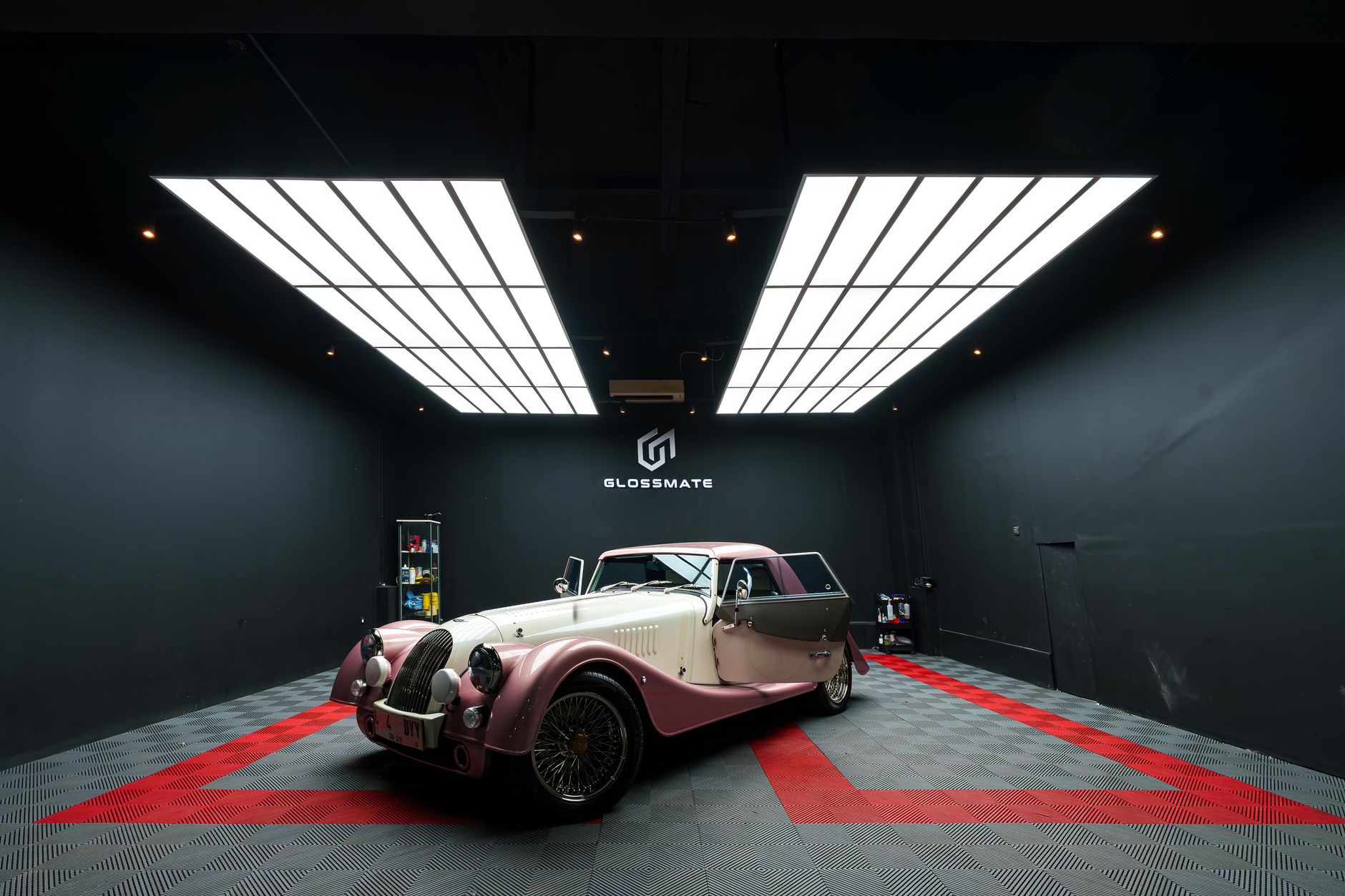 A classic pink and cream vintage car showcased in a modern, sleek showroom with LED lighting.