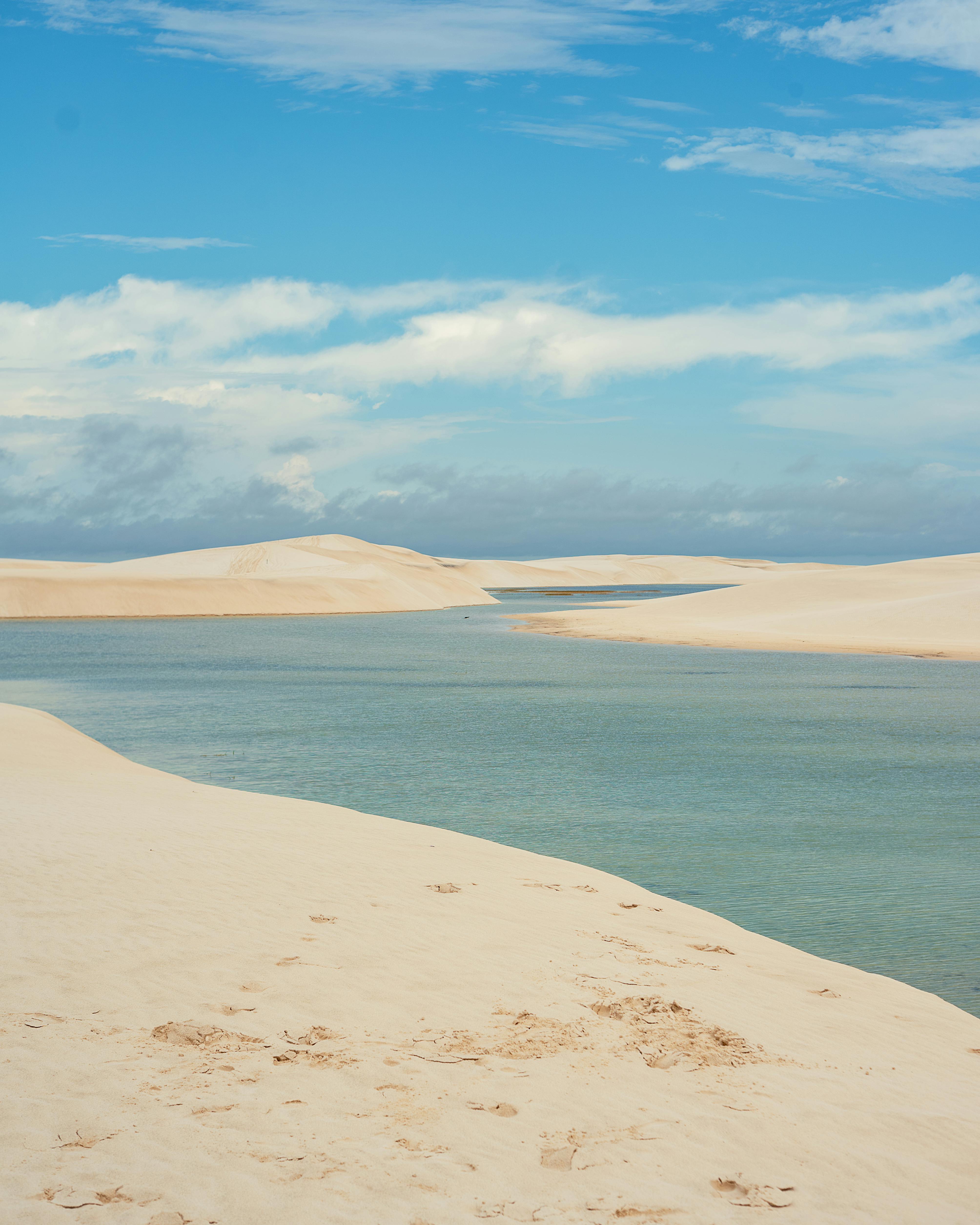 Stunning view of sand dunes and clear blue lake under a vivid sky in Maranhão, Brazil.