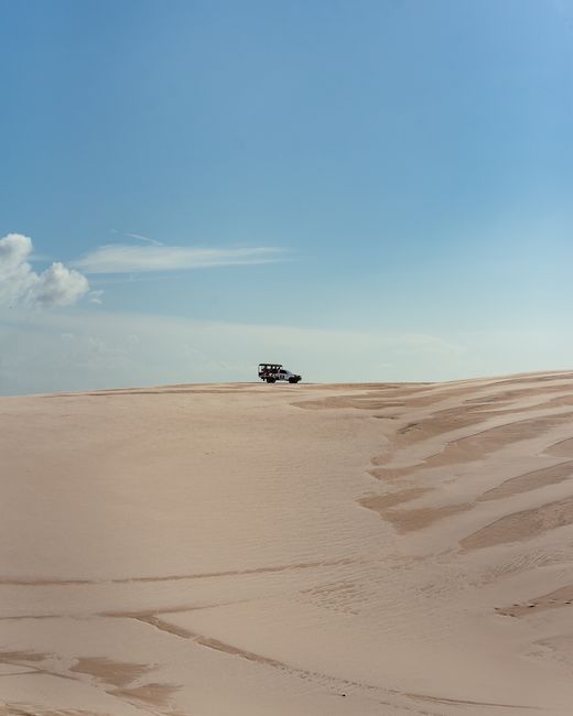 Explore the thrilling Brazilian dunes with a 4x4 under the clear blue sky.