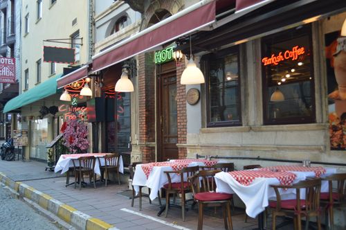 Free A street-side restaurant in Istanbul featuring outdoor seating with red checkered tablecloths and vibrant signs. Stock Photo