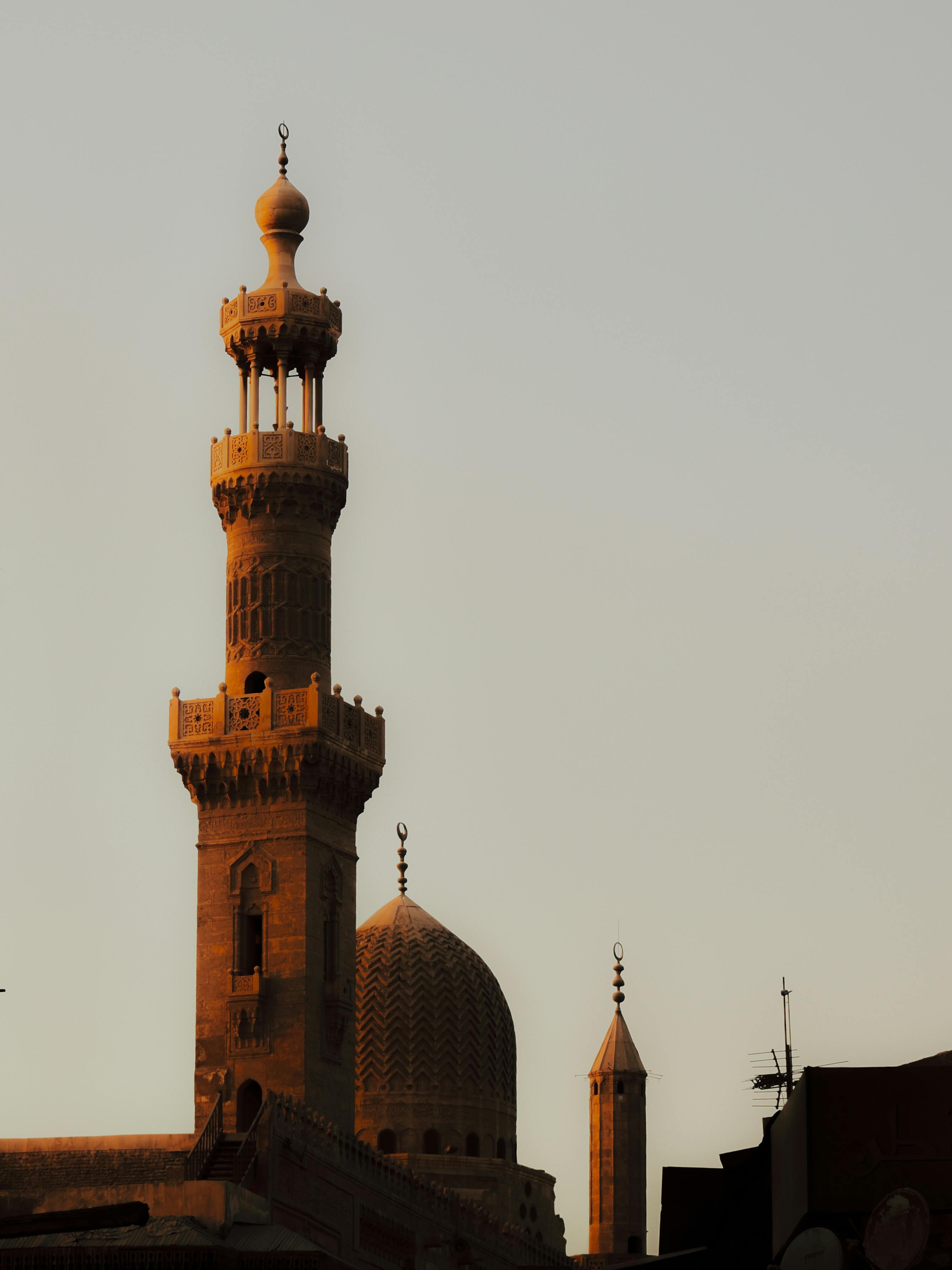 Dramatic silhouette of historic mosque towers during sunset in Cairo, Egypt.