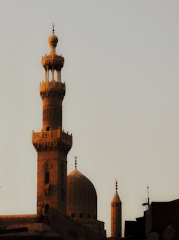 Dramatic silhouette of historic mosque towers during sunset in Cairo, Egypt.