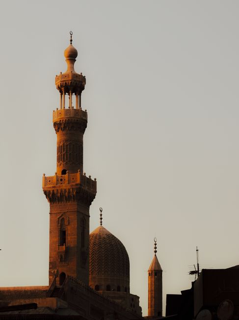 Dramatic silhouette of historic mosque towers during sunset in Cairo, Egypt.