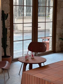 Warm indoor café scene with wooden chairs and table by a window.