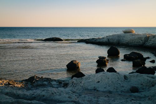 Free Peaceful seaside scene showcasing rocky coastline and tranquil ocean during sunset. Stock Photo
