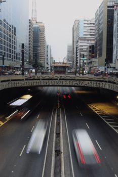 Long exposure of rushing traffic under a bridge in an urban setting at dusk. Dynamic and vibrant city life.