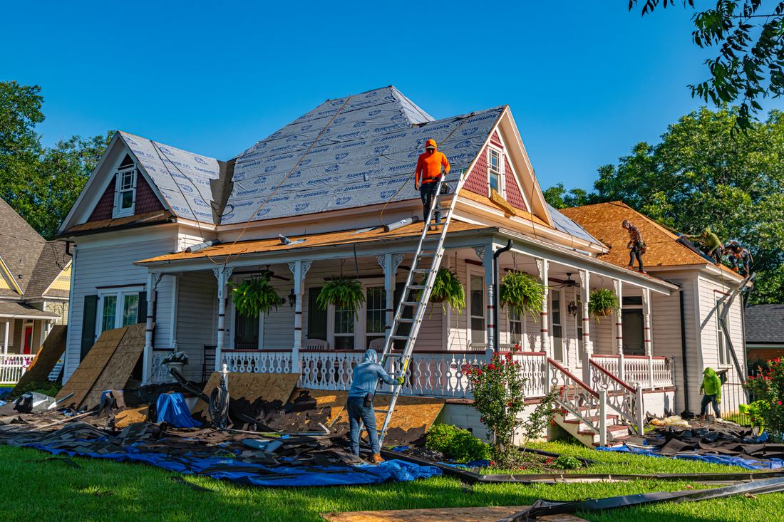A sloped roof being re-roofed, with the deck stripped to underlayment and new covering going on