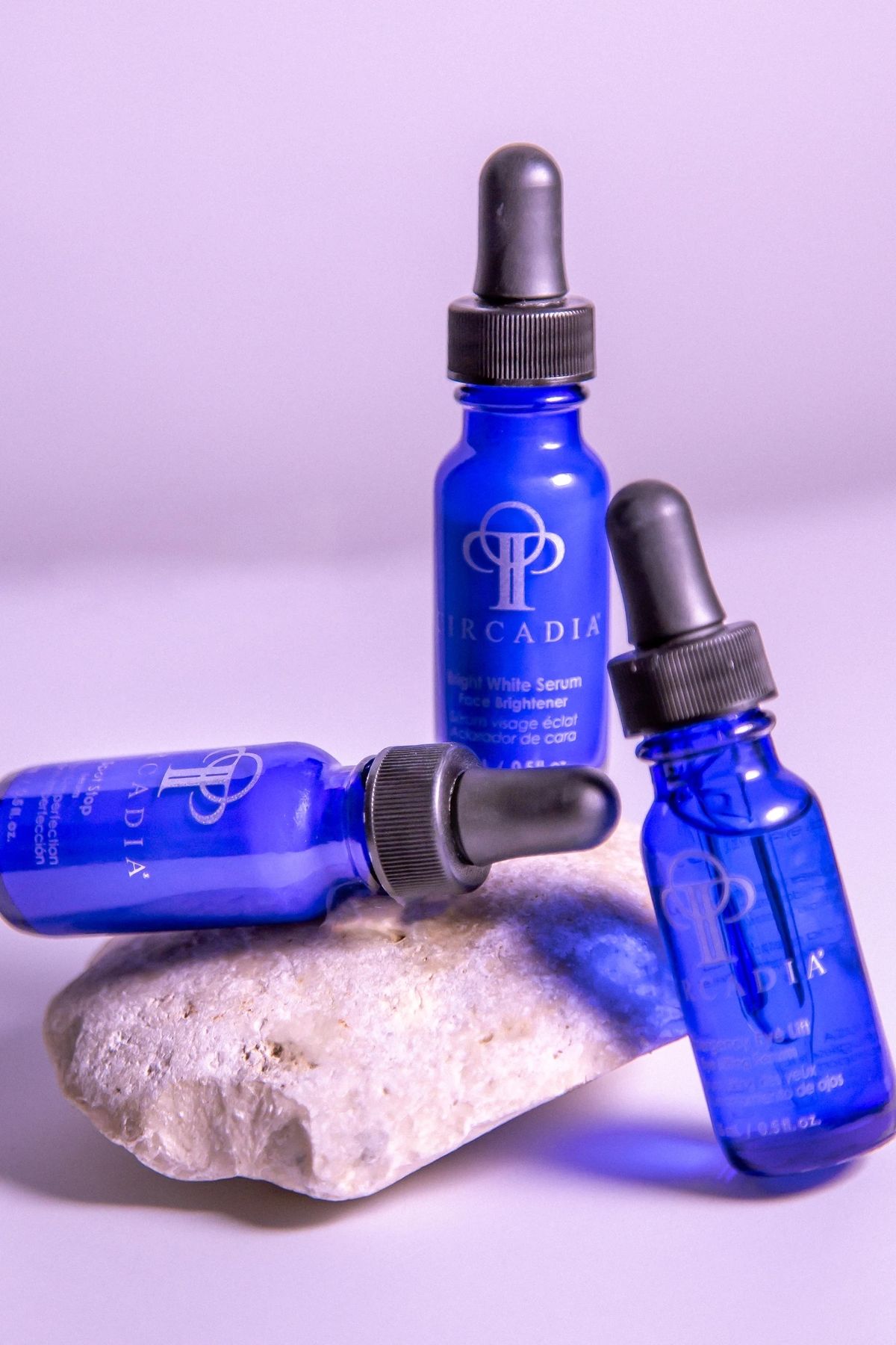 Blue glass serum bottles with droppers on a stone surface