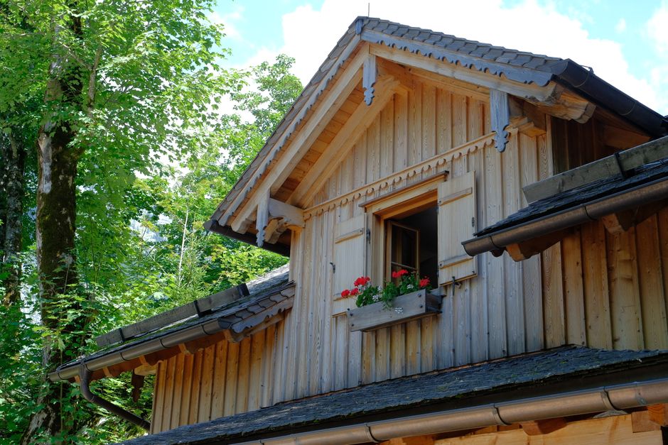 Beautiful wooden house in Altaussee, Austria with red flowers in a window box. Serene summer vibe