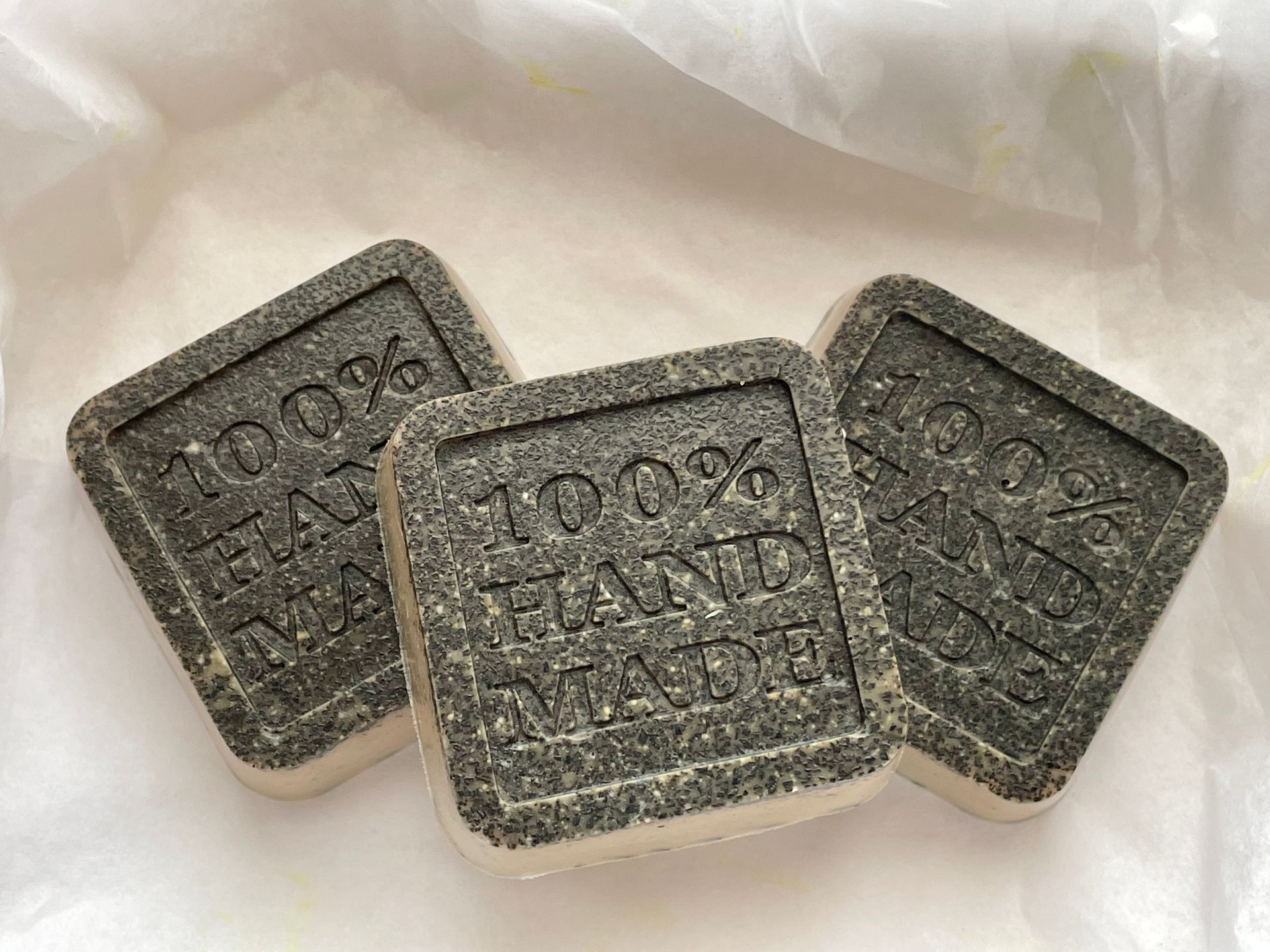 Close-up of three handmade soap bars with '100% Hand Made' inscription.
