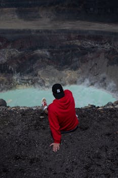An adventurous person overlooks Kawah Ijen's sulfuric crater lake in East Java, Indonesia.