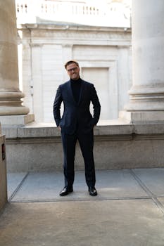 Confident man in business attire standing between grand columns, exuding professionalism and elegance.