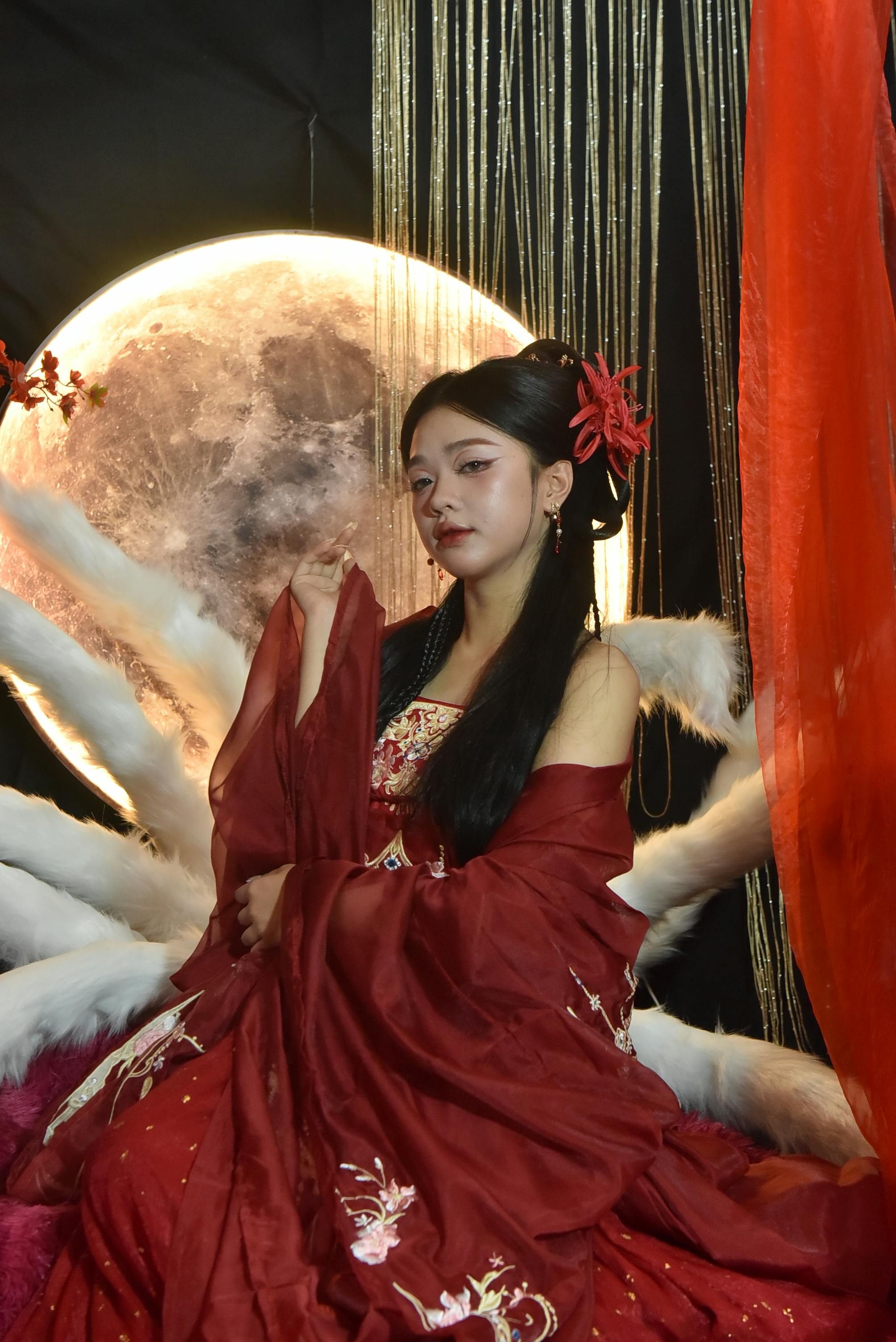 Ücretsiz Çarpıcı aydınlatma ve dekor eşliğinde canlı kırmızı geleneksel Asya elbisesi giymiş kadın. Stok Fotoğraflar