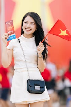 Smiling woman holding Vietnam flag and ticket, celebrating National Day outdoors.