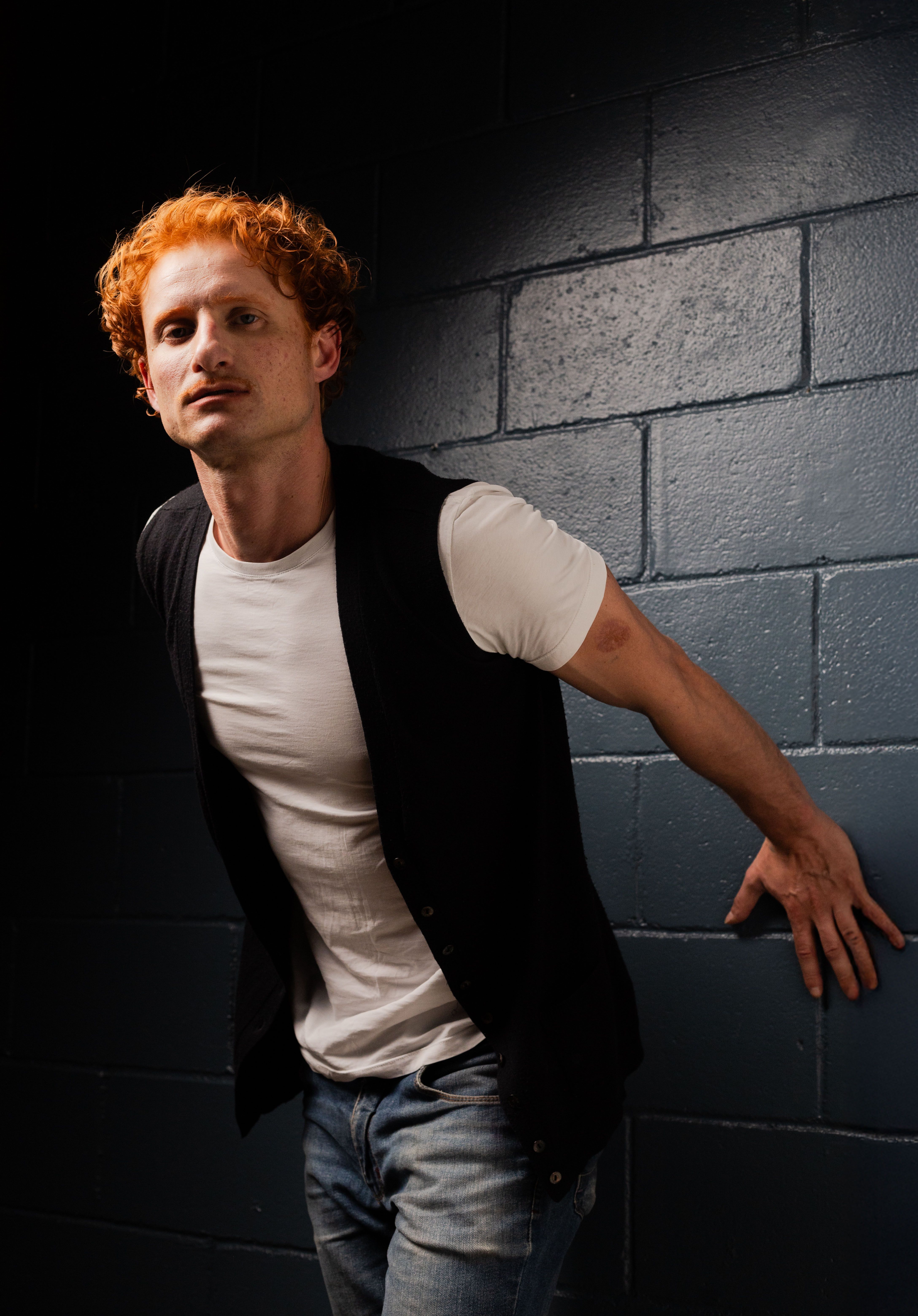 Captivating portrait of a red-haired man in a studio showcasing dramatic lighting and shadow play.