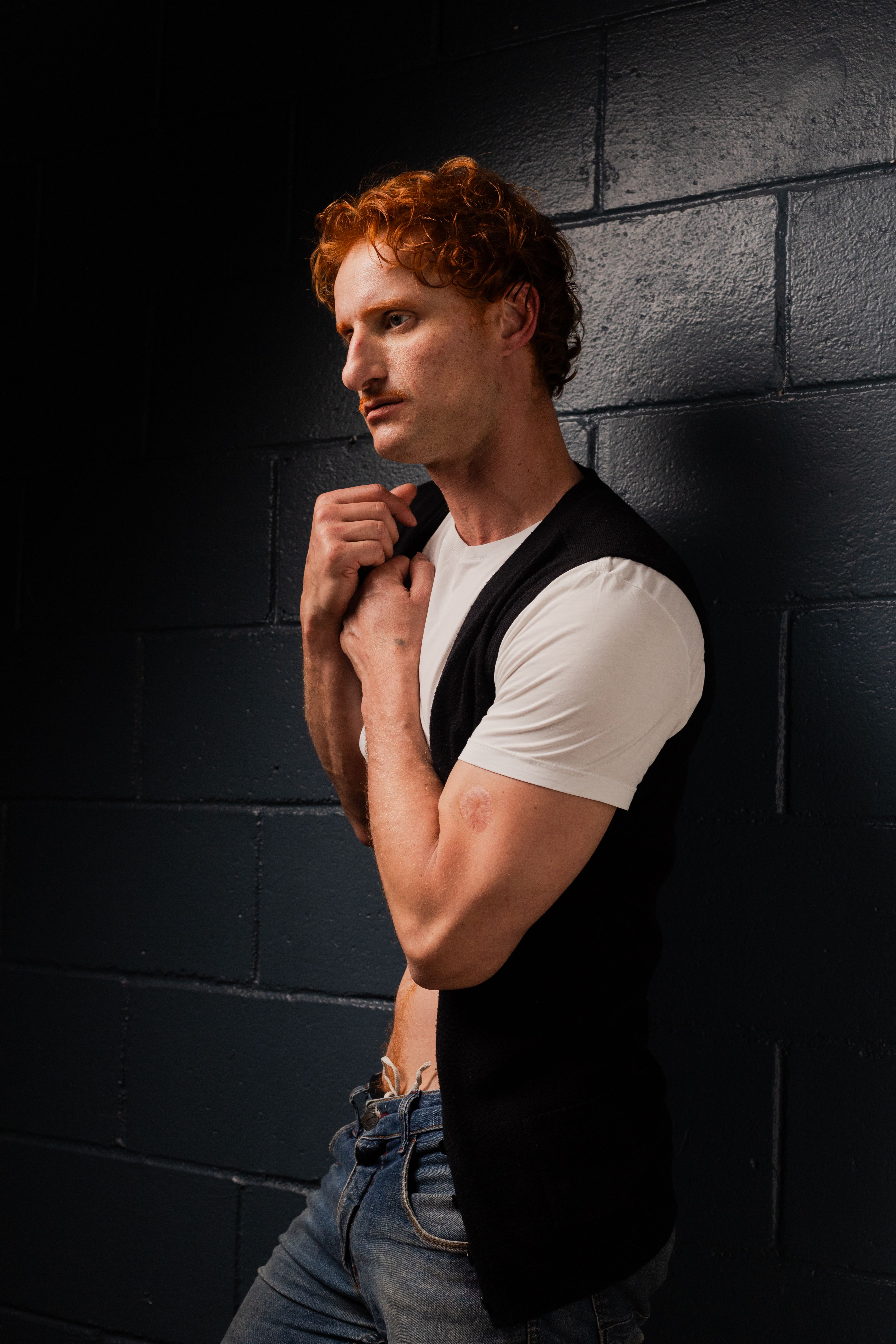 A creative portrait of a red-haired man in a studio using light and shadow contrast.