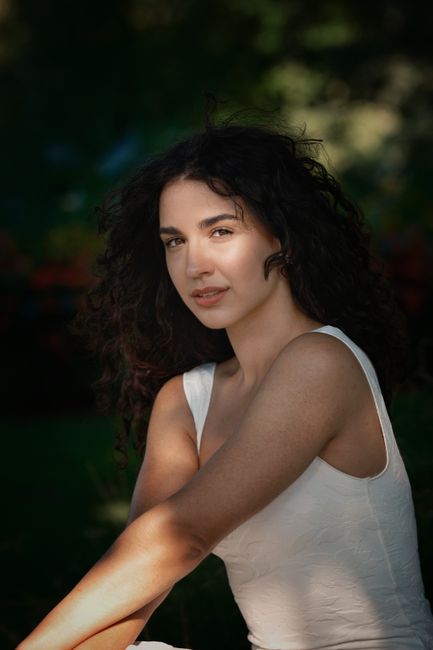 Natural portrait of a woman in a sunlit garden, showcasing serene beauty and tranquility.