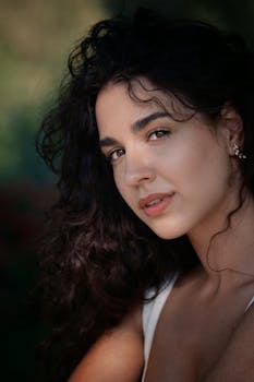 Close-up portrait of a woman with curly hair and elegant earrings in natural light.