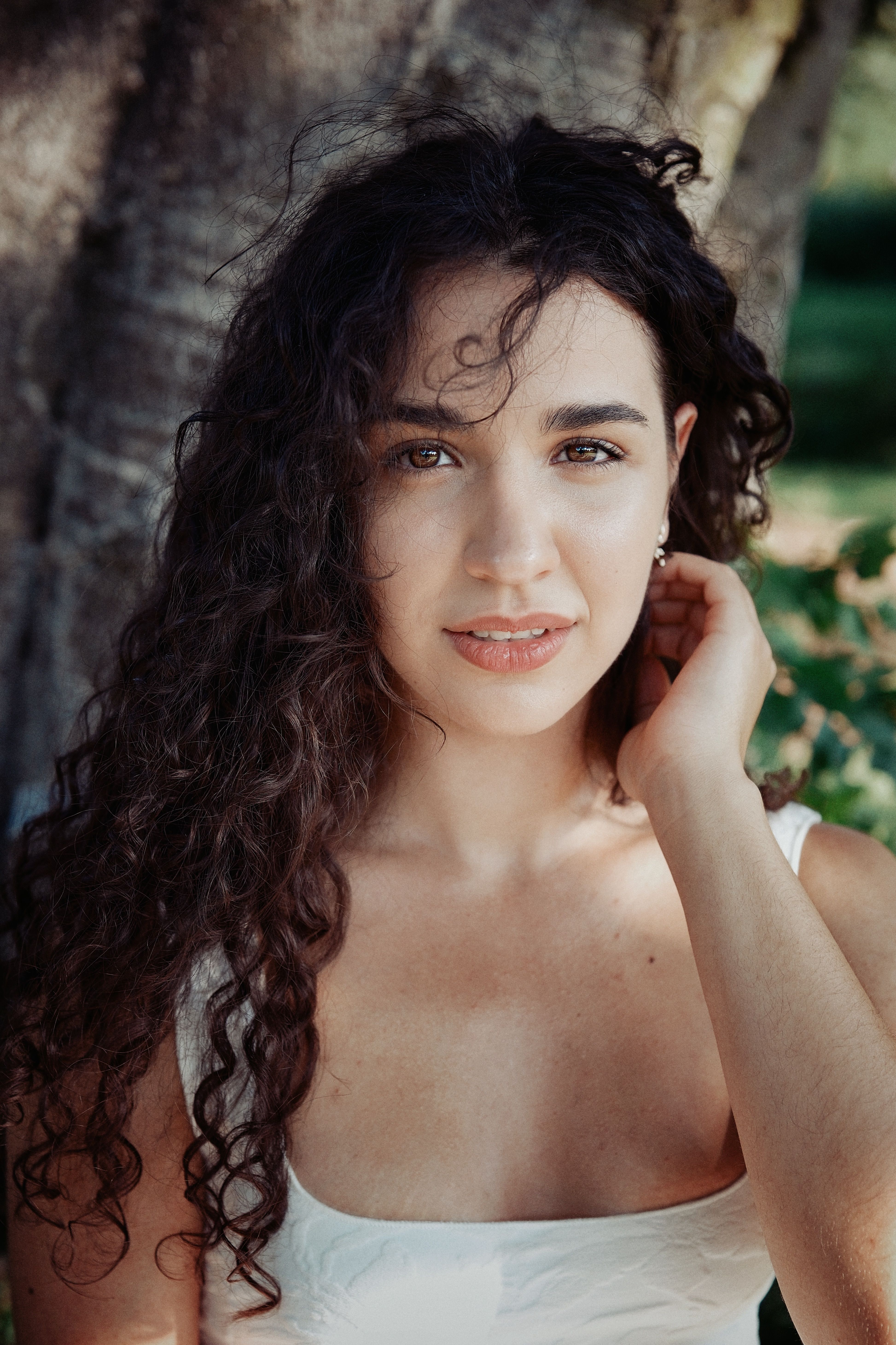 Natural light portrait of a young woman with curly hair, outdoors in summer.