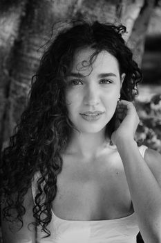 A captivating black and white portrait of a young woman with curly hair.