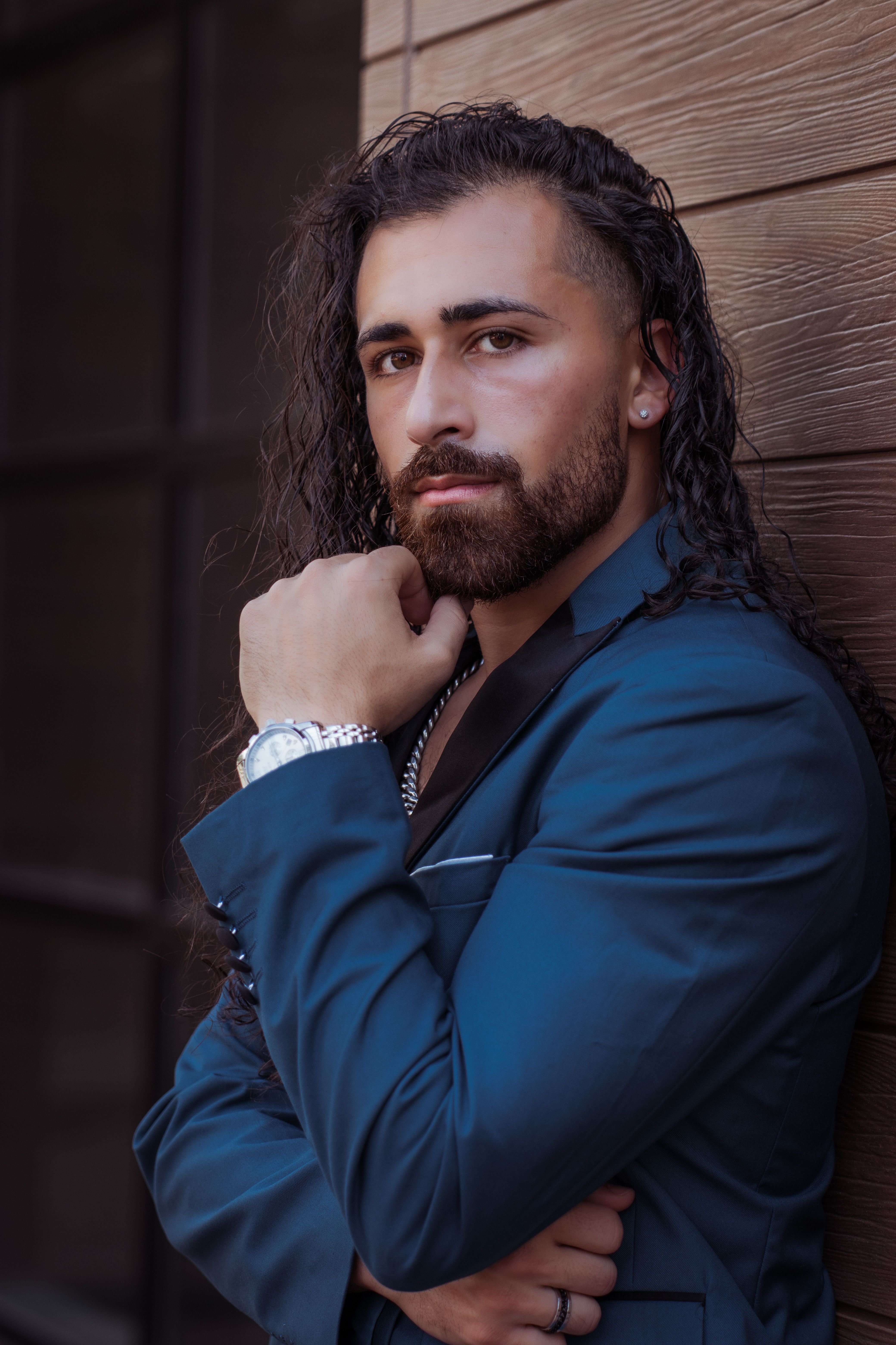Confident man in stylish blue suit posing outdoors with thoughtful expression.