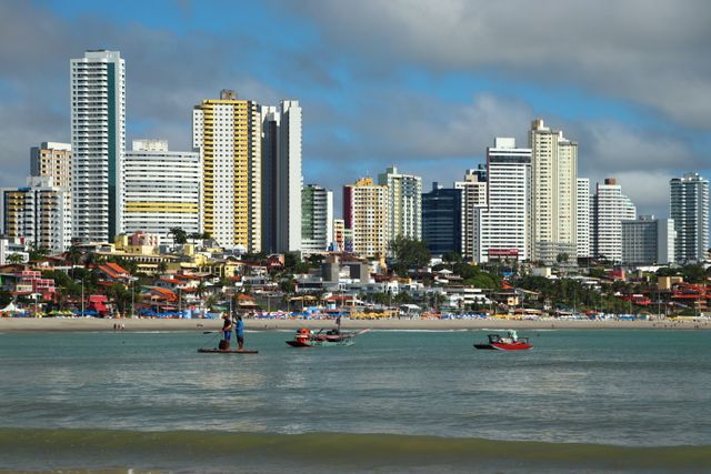 Vibrant skyline of Natal, Brazil with fishermen at the beach. Captivating seascape with tall buildings.