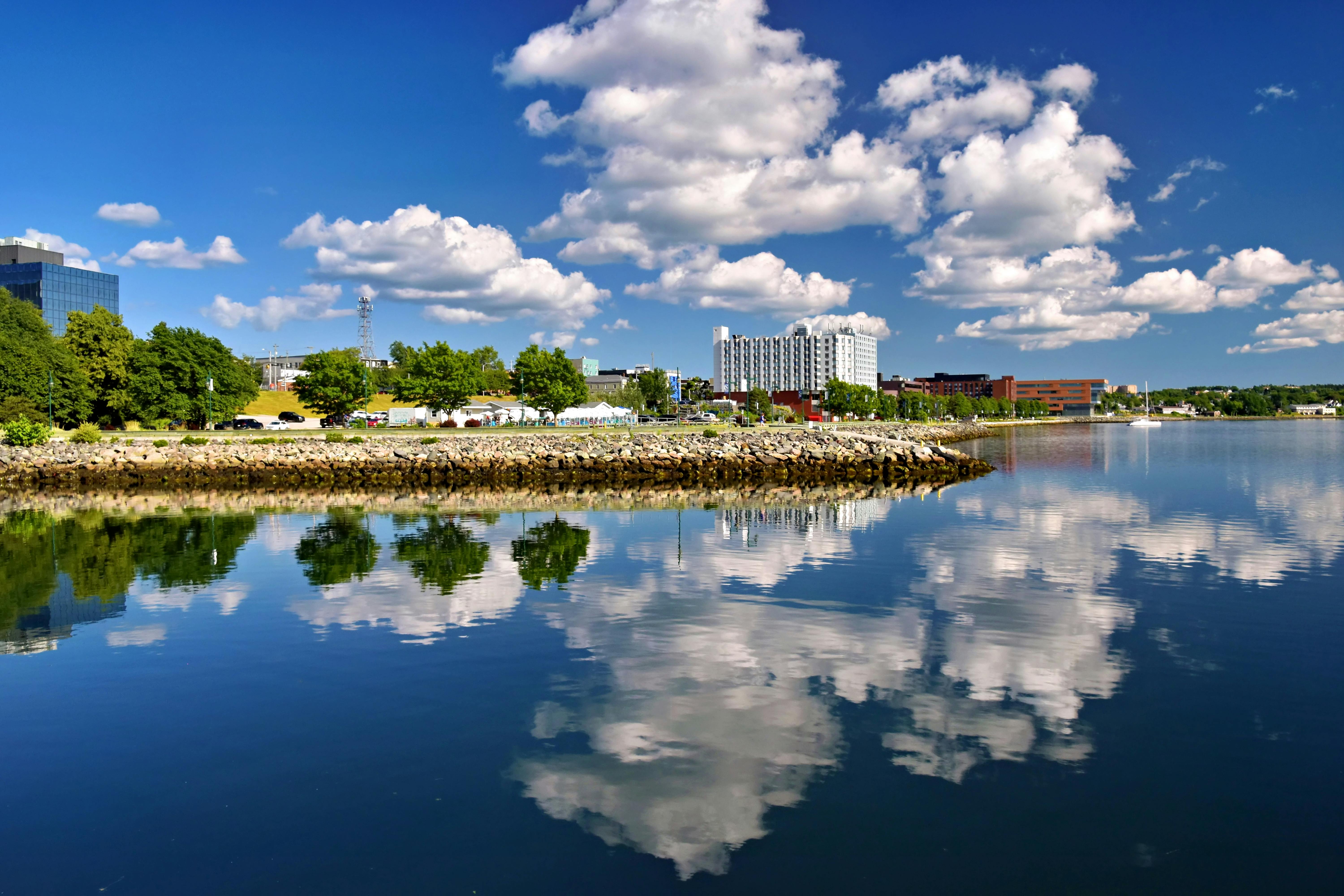 Beautiful summer view of Sydney, Nova Scotia's waterfront with clear reflections and blue sky.