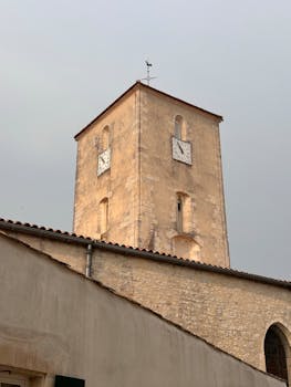 Ancient stone clock tower under a cloudy sky, showcasing European architecture.