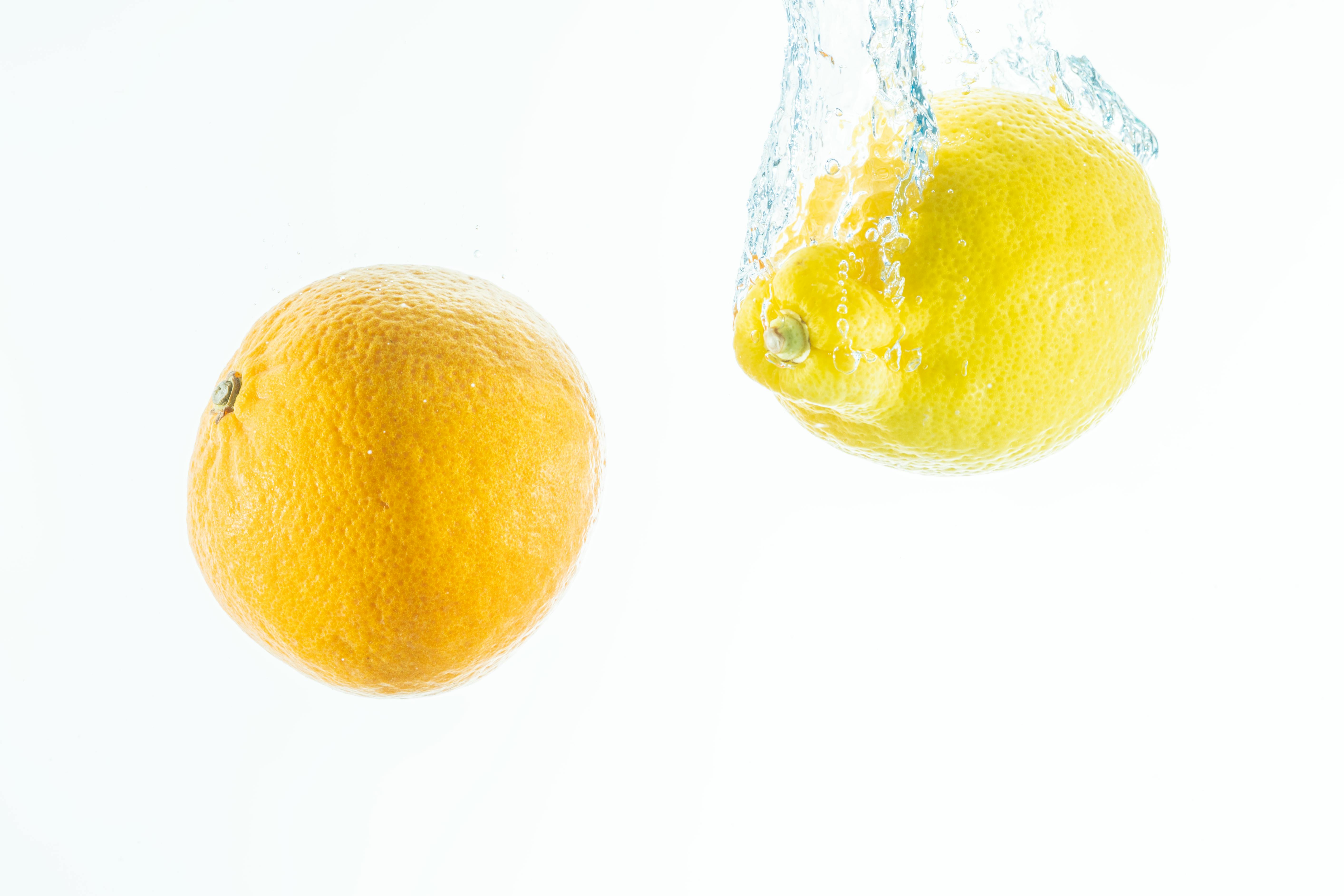 Orange and lemon splashing in water on a white background, evoking freshness and vitality.