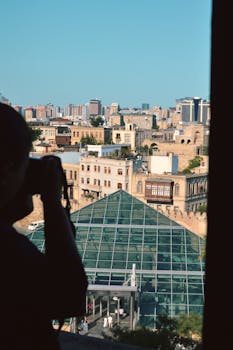 A cityscape view featuring a photographer in silhouette capturing urban architecture.